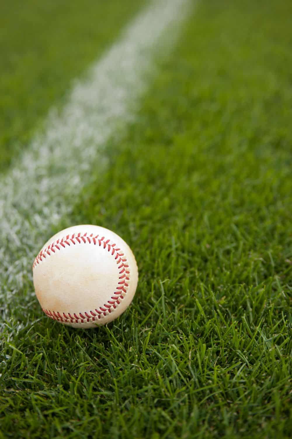 A baseball rests on lush artificial turf near a crisp white chalk line, showcasing the quality of artificial grass installation in Mesa AZ.